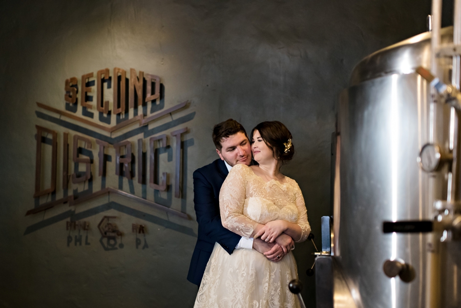 A newly married couple hug in a brewery.